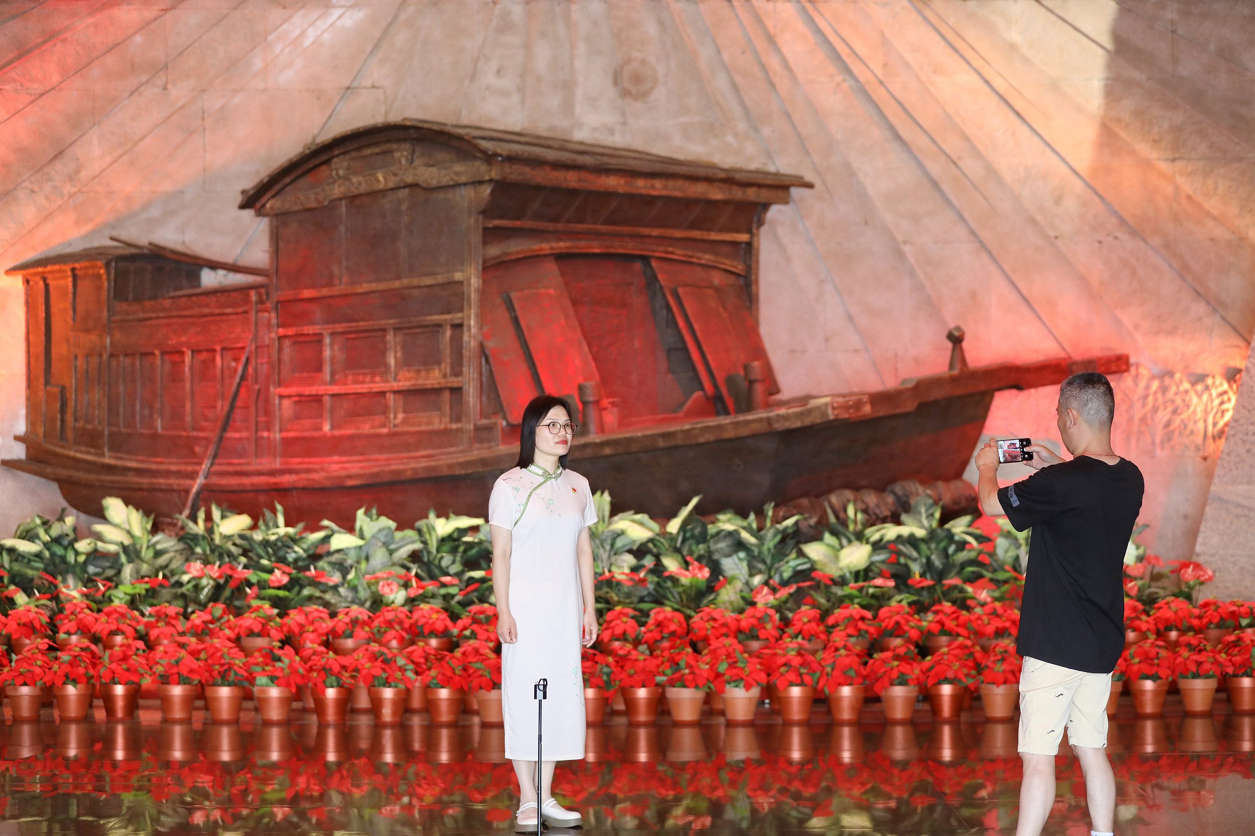 2025年6月24日,浙江嘉興,游客在南湖革命紀(jì)念館與紅船雕塑合影。(圖片來(lái)源:視覺(jué)中國(guó))